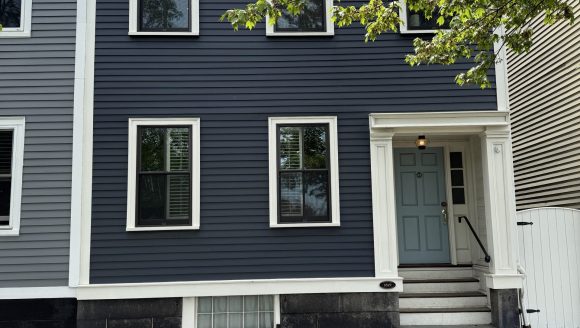 Wood Clapboard House with side entry, stone foundation and side gable roof.